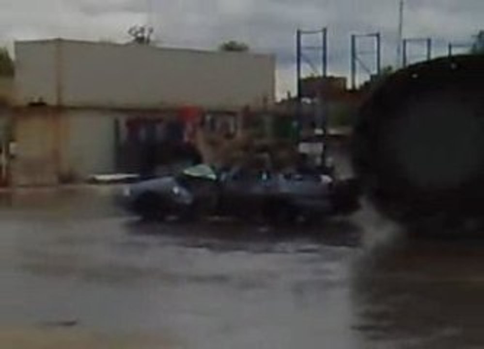 Pelleteuse géante lache de l'eau sur une voiture