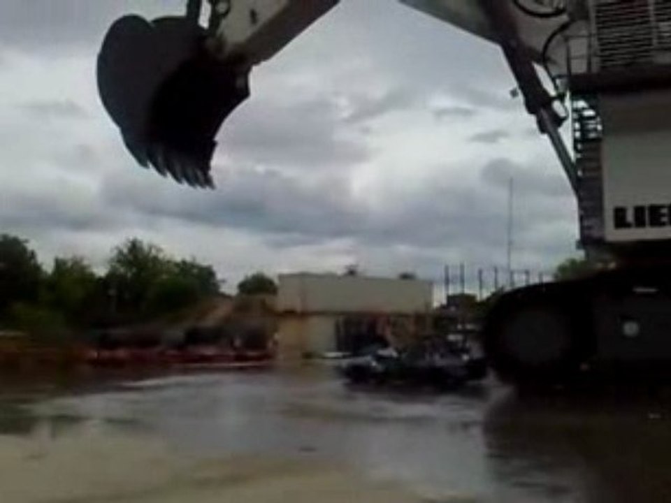 Pelleteuse géante lache de l'eau sur une voiture