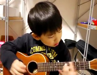 Un enfant joue du ukulele et chante