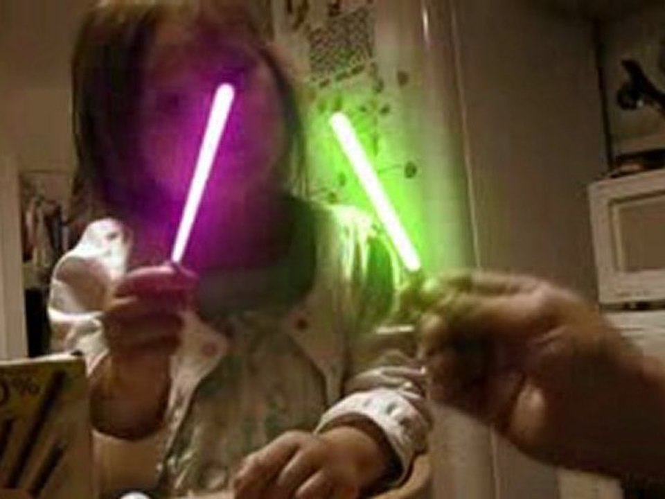 Une petite fille et son papa font une partie de sabre laser