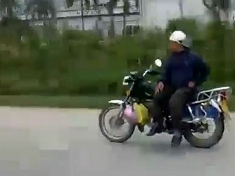 motard roule assis sur le coté sans tenir son guidon