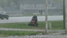 Il folle dell'anno falcia l'erba mentre grandina