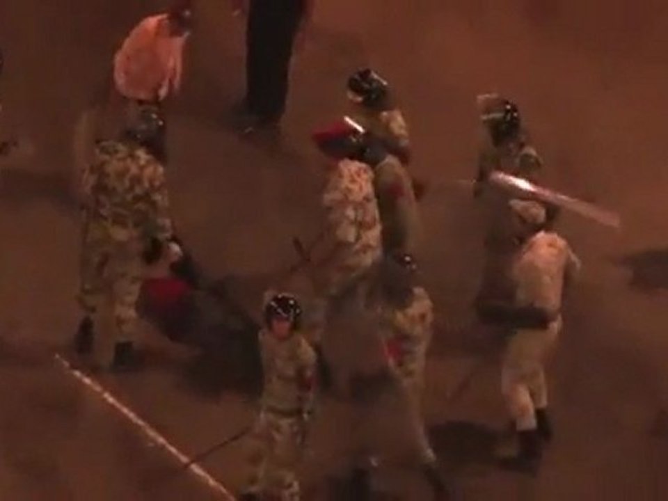 Plus de 10 officiers entourant un jeune copte allongé sur le sol lui donnant des coups de pied et de mattraque