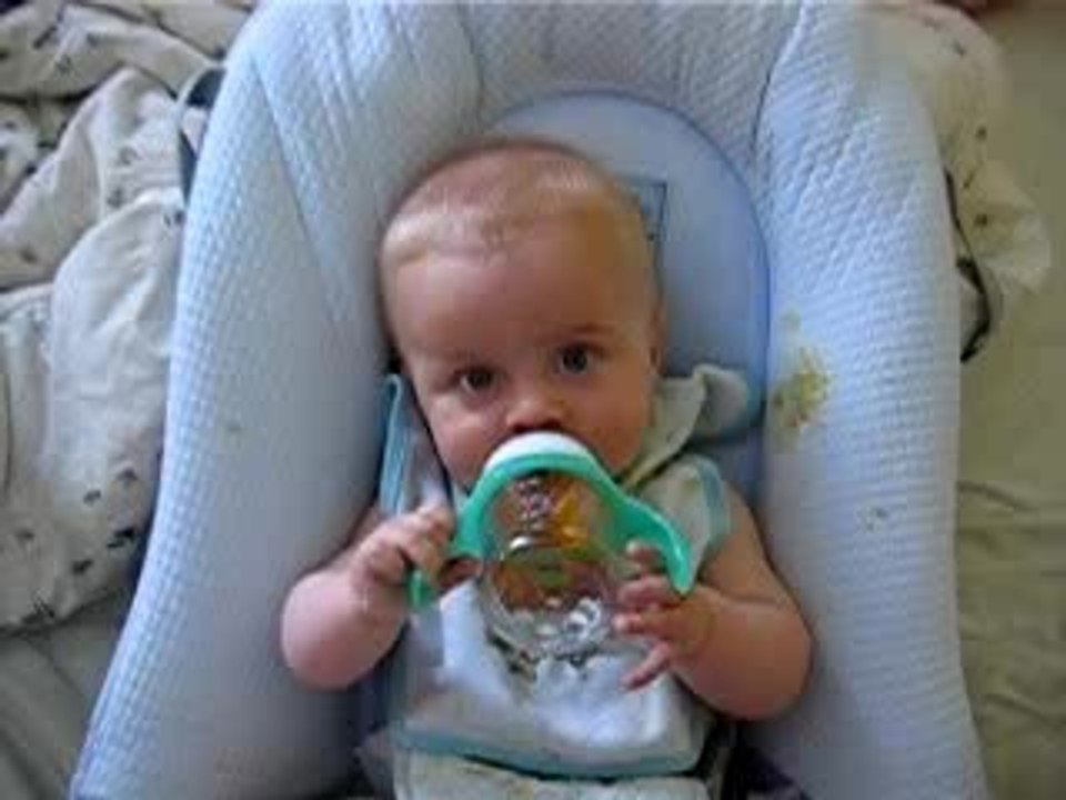 Vincent essaye de boire son biberon seul