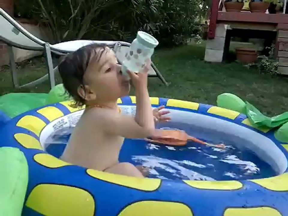Elyas dans la piscine avec son biberon