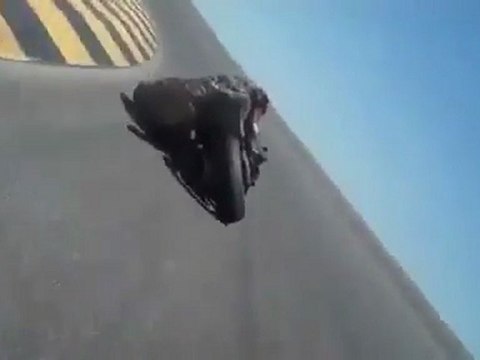 Un motard qui prend vraiment de langle, à frotter son casque sur la piste