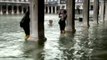Tourists wade in knee-deep water in Venice