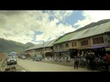 Kashmir traffic past a small bazaar with a time-lapse of clouds over the mountains