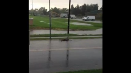 Man floats down rainy residential road