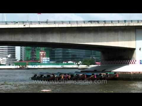 Colorful tourist long-tail boats parked under bridge in Bangkok