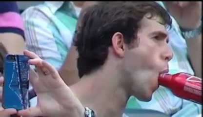 A baseball fan sucking a bottle of Budweiser while watching the game in the crowd !!
