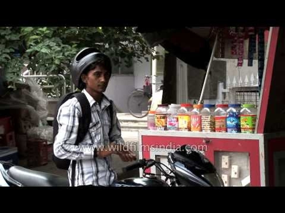Man on bike buying cigarettes from a roadside shop