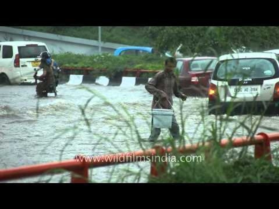 Cars driving through puddle of rain water in Delhi