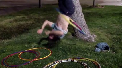 Guy Hula-Hoop upside down , hanging from a tree!