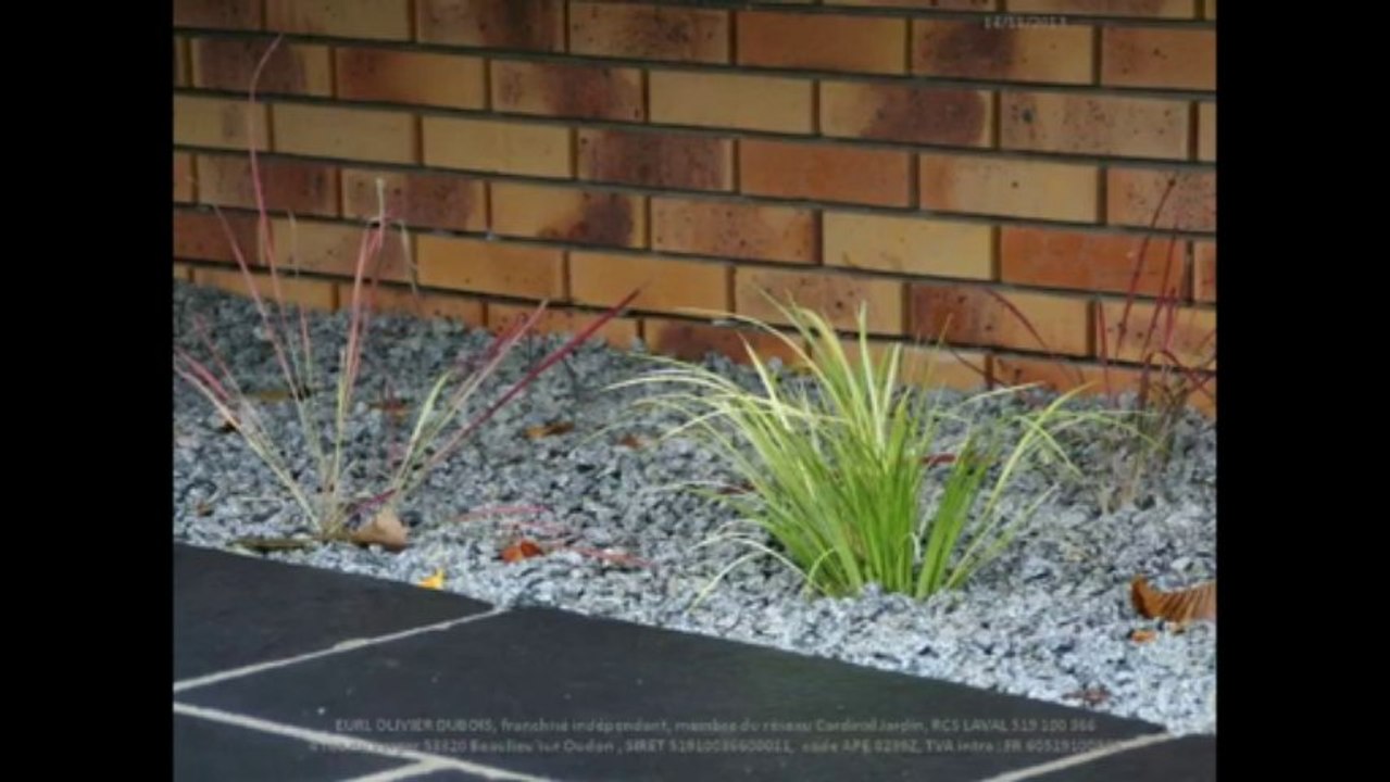 Aménagement autour d’une maison :Enrobé noir à chaud et dallage en pierre naturelle, brise vue en palis ardoise et treillage bois avec chèvrefeuille et paillage en gravier granit.