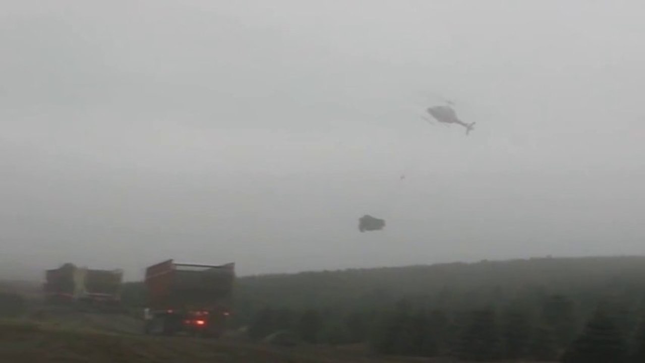 Un hélicoptère charge des sapins de Noël dans des camions