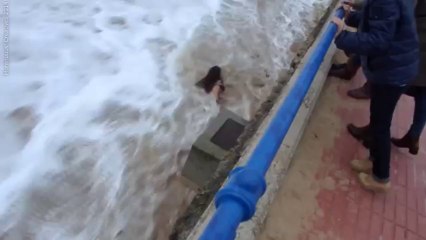 Une femme emportée par une vague