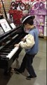 Un enfant surdoué fait une démo de piano dans un magasin.