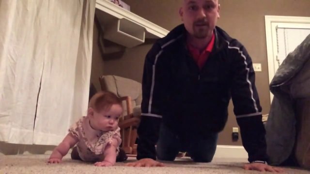 Un bébé coach son père pendant une séance de musculation
