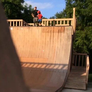 Un père pousse son fils du haut d'un rampe de skate