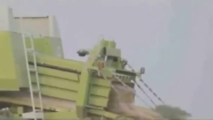 Un homme passe dans une machine à faire des ballots de paille