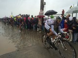 Les coureurs roulent sur les pavés sous la pluie