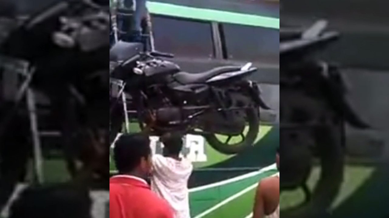 Mettre une moto sur un bus en la portant sur la tête