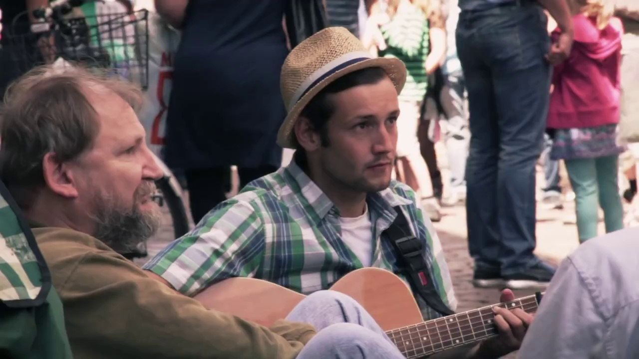 3 German students helping a homeless guy play music to win some money