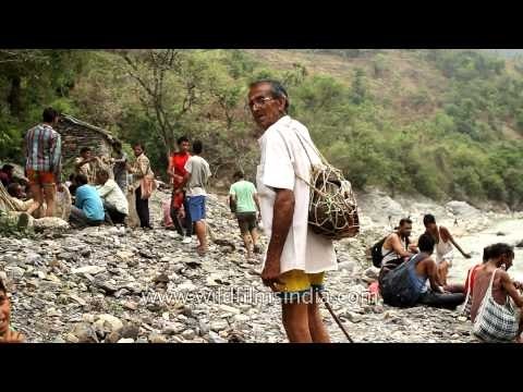 Villagers walk on a makeshift bridge to cross River Aglar