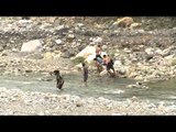 Village boys cross heavily flowing river Aglar
