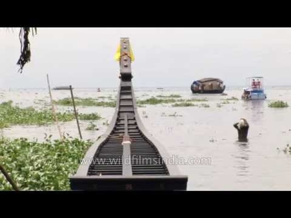 Man bathes next to his new Snake Boat in the backwaters of Kerala