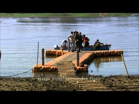 Tourists step onto dry land after a riverine expedition on the River Denwa