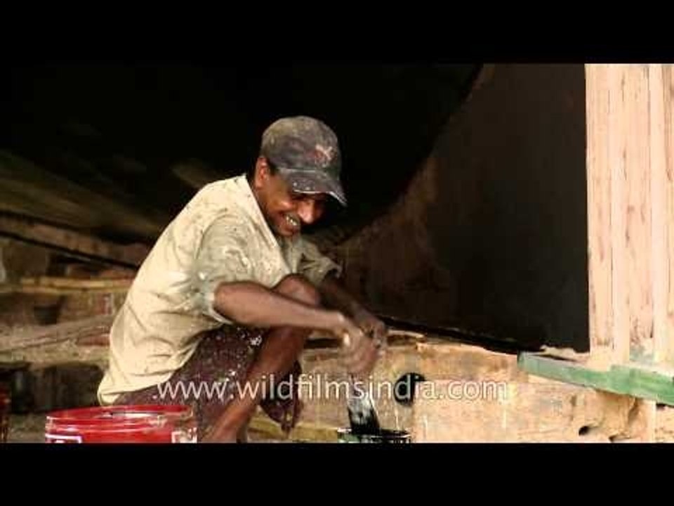 Smiling workers painting the large fishing boat - Kochi