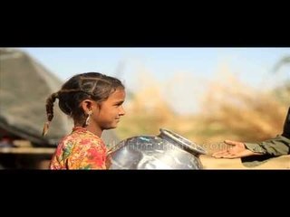 Cute village girl sweeping outside her hut in Rajasthan
