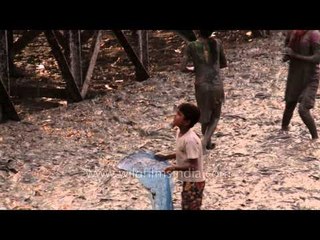 Poor children standing in mud, with nets to collect coins in