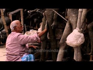 Idol maker of Kumortuli shaping the feet of the sculpture