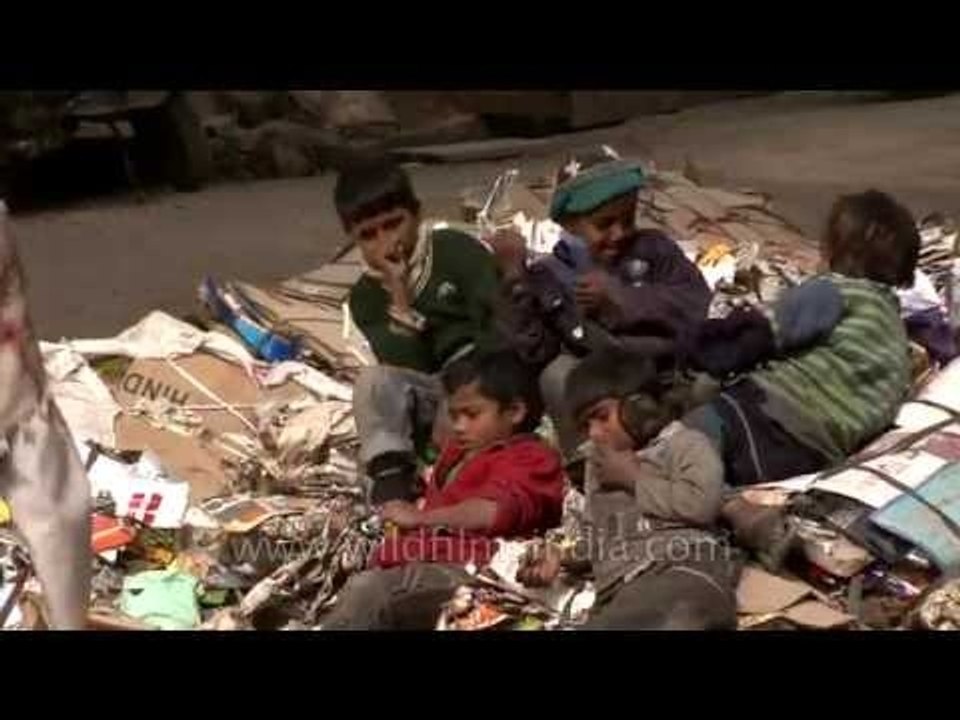 Rag picker kids sit down comfortably in their heap of trash