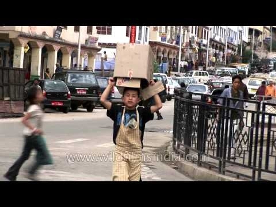 Boy crossing the road, carrying the box in his head in the streets of Bhutan