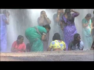 Women wearing sarees getting wet and having fun under waterfall