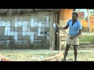 Man axes wood outside home in Arunachal