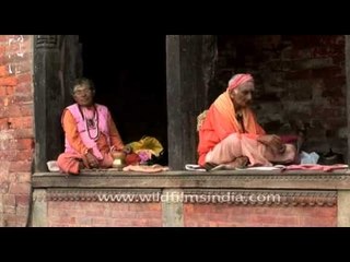 Pujaris sitting on the window-sill of a temple in Nepal