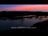 Red sky sunset as villagers cycle by, Uttar Pradesh