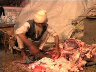 In an abattoir: a butcher cutting up a goat