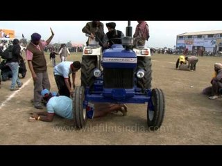 Tractor torture - men going under massive tractor wheels!