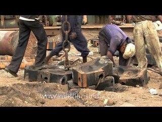 Crane lifting heavy metal blocks at Alang