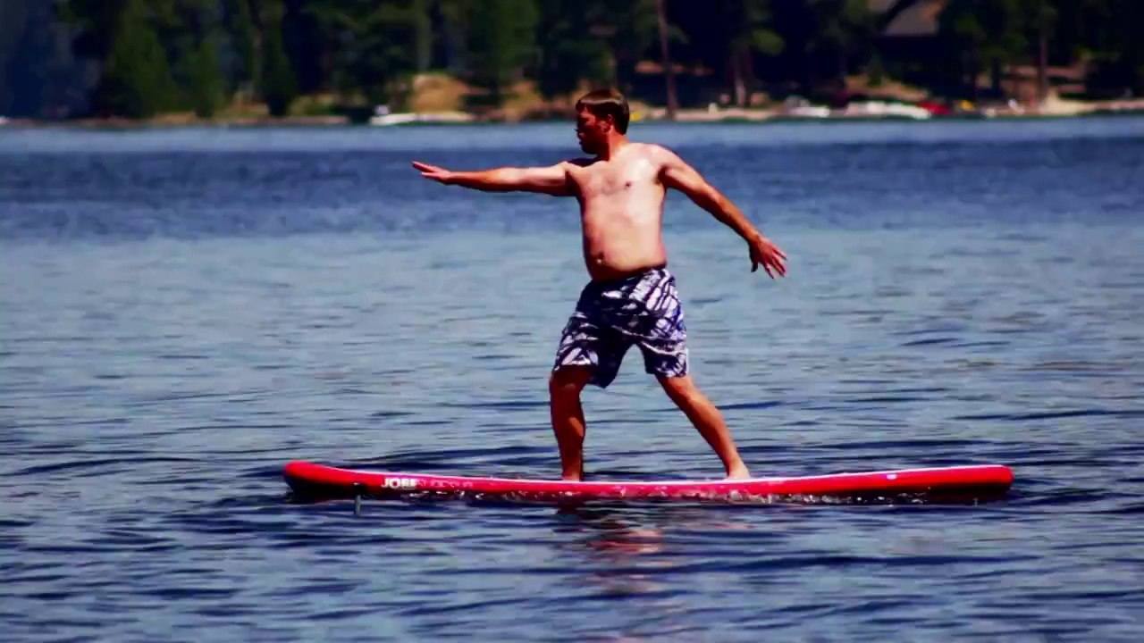 Chubby man exercises on paddle board (SUP) for 1st time.