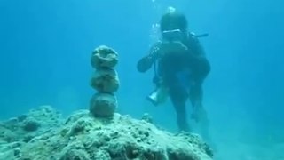 diver overturns a rock formation with a bubble