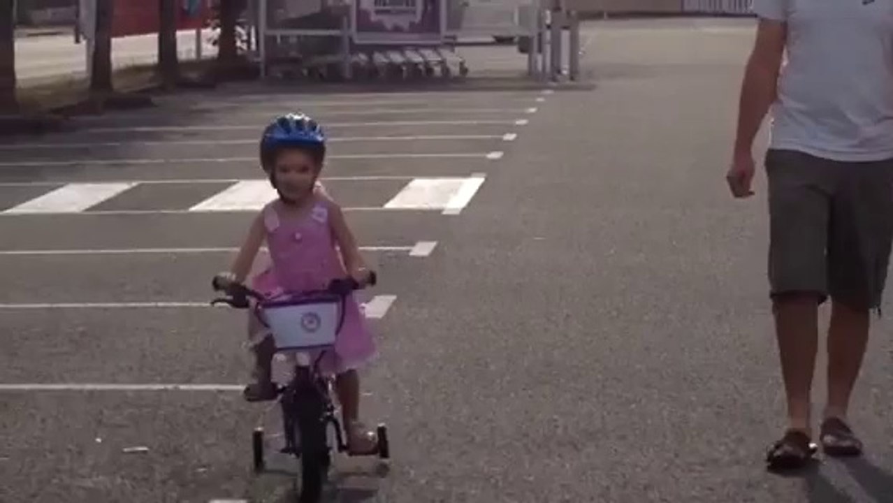 Jeanne fait du vélo avec les roulettes
