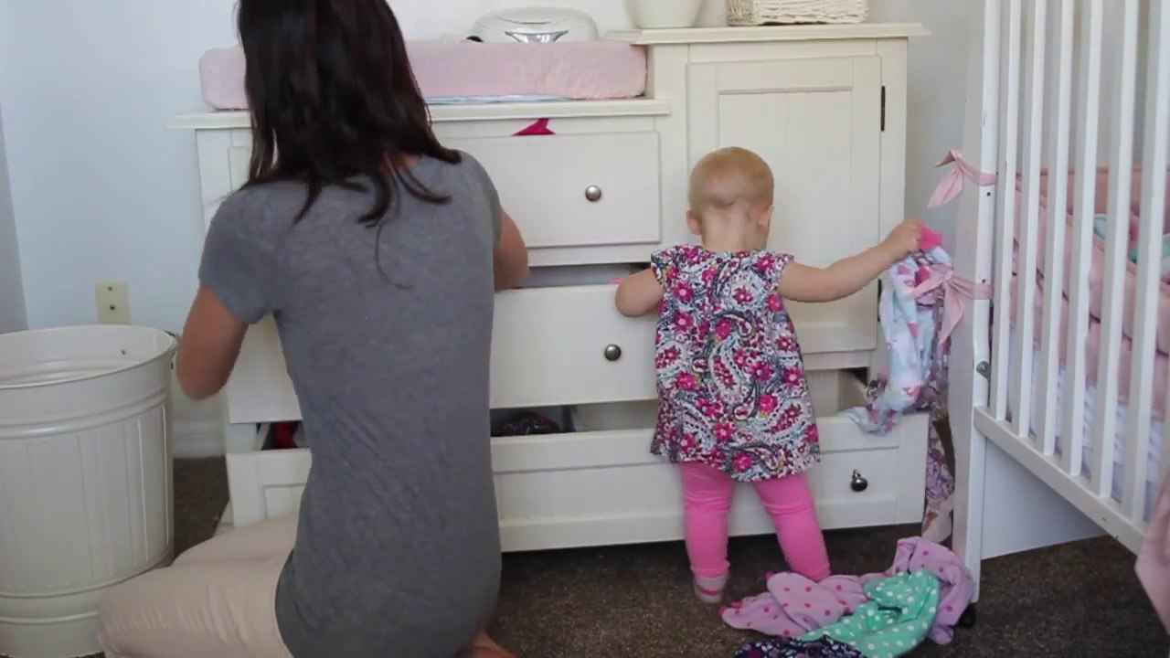 Mom folding laundry is helped by her young daughter...