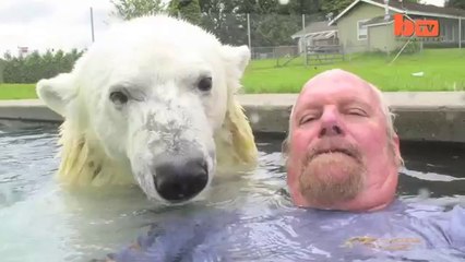 Un homme embrasse et se baigne avec un ours polaire